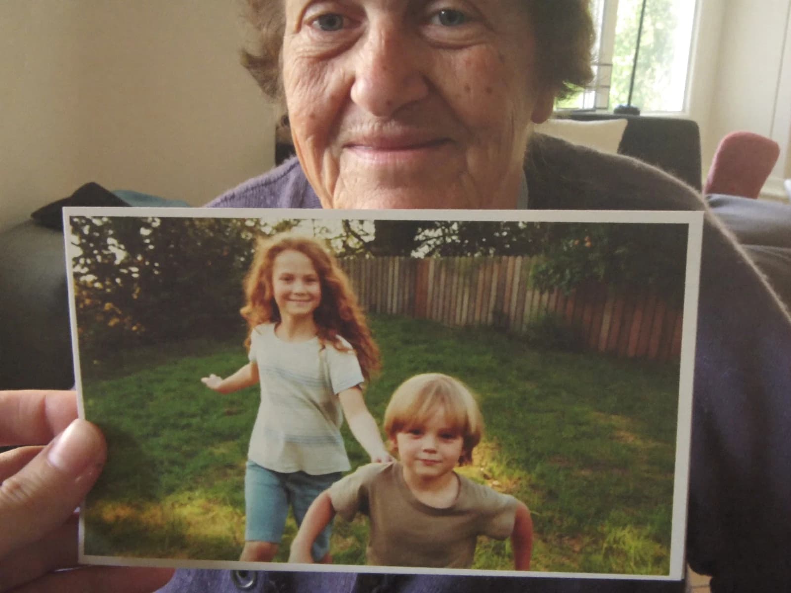 A grandmother at home smiling as she looks at a FamilyLetter postcard