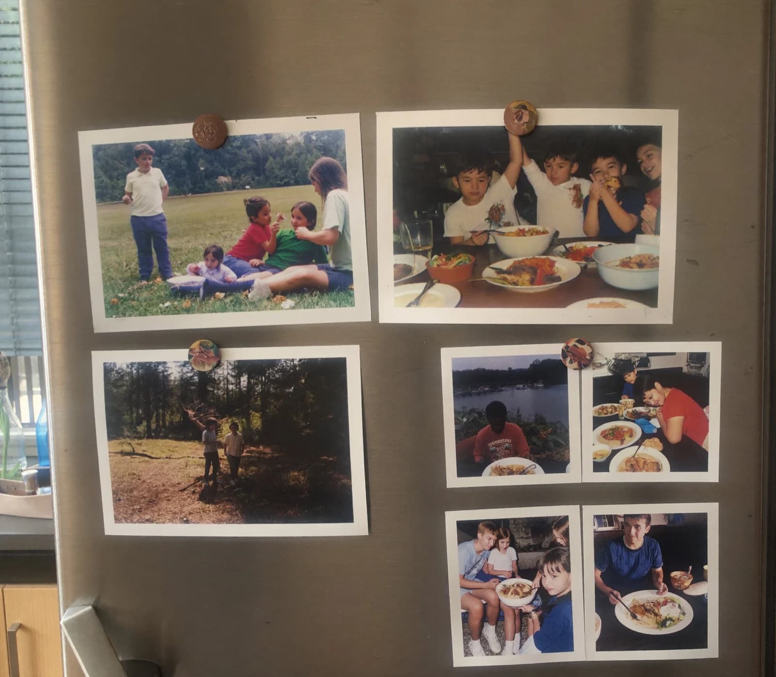 Five FamilyLetter postcards held to a refrigerator door with magnets, some showing one photo and some a collage