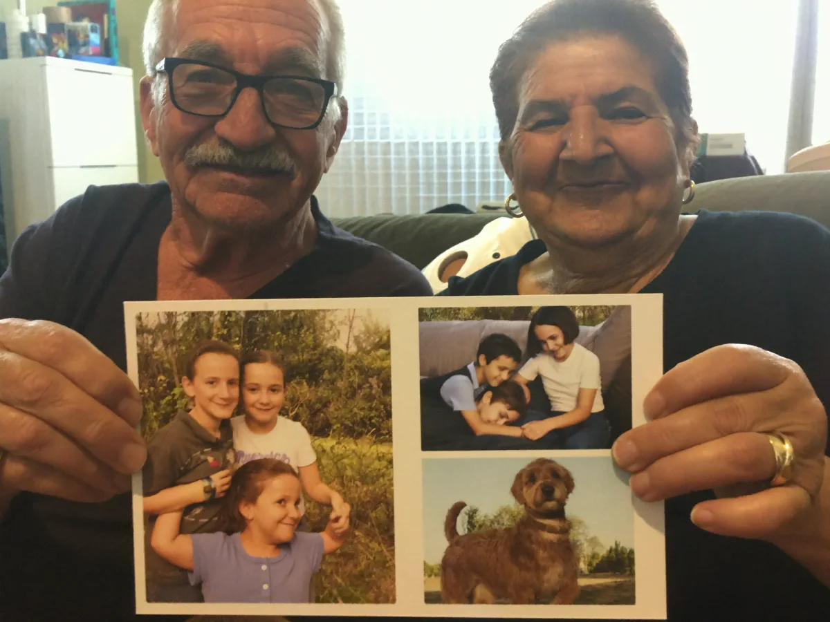 A grandmother and grandfather holding a collage postcard from their family